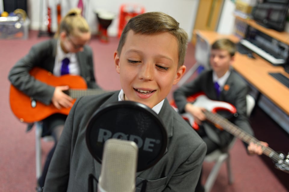 Boy singing into microphone with band